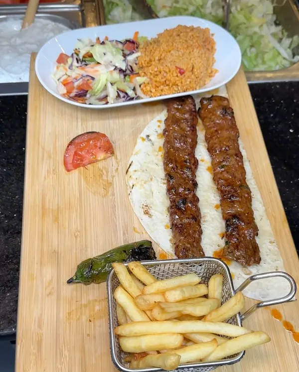 Deux brochettes Adana sur la planche, avec blé, frites et salade