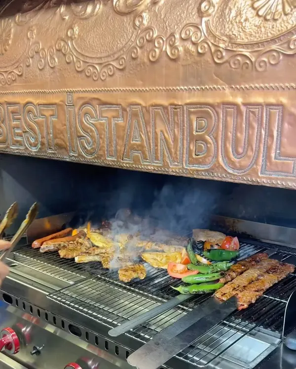 Brochettes sur le grill, sous la hotte en cuivre gravée Best İstanbul