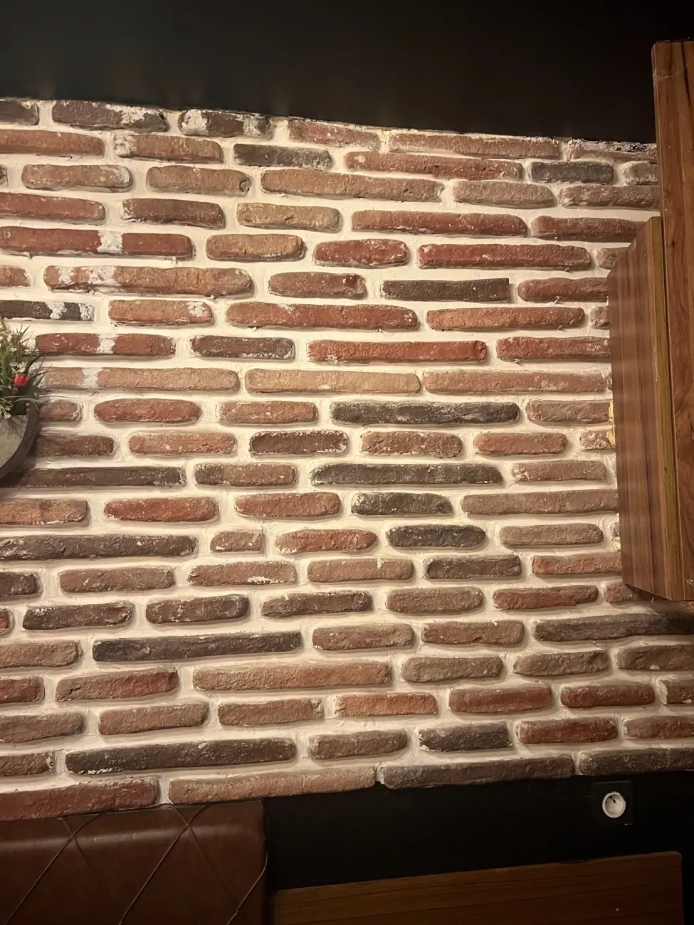 Le mur de briques au-dessus de la banquette en cuir capitonné