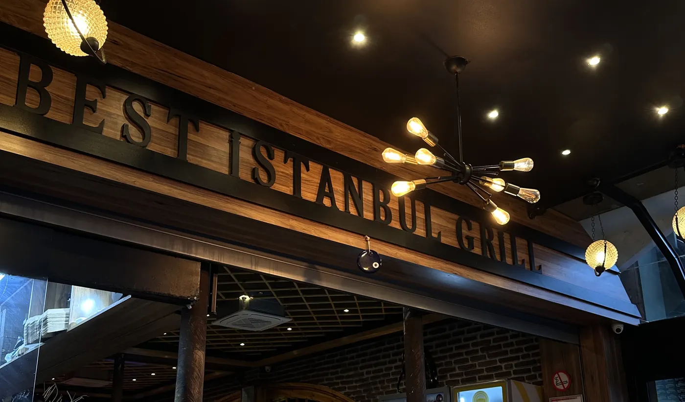 La salle le soir : lettrage Best Istanbul Grill en bois et suspensions en verre